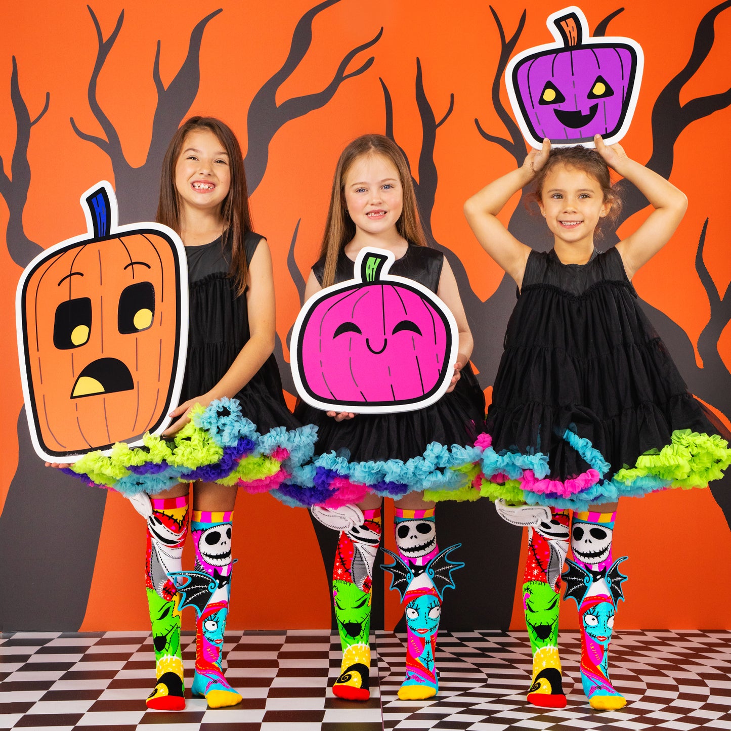 Three girls wearing colorful Jack Skellington Halloween knee high socks with spooky character designs.