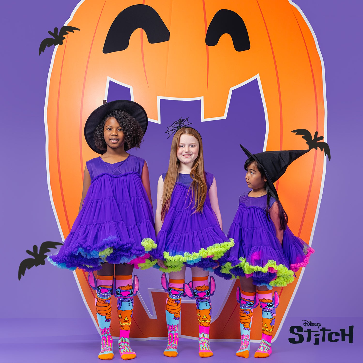Three kids wearing purple Halloween costumes styled with Disney Stitch neon trick or treat knee high socks.