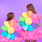 Girls wearing cute daisy shaped backpacks in bright rainbow colors