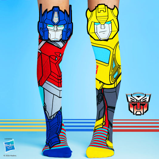 Transformers knee high socks featuring Optimus Prime and Bumblebee character graphics in bright red, blue, and yellow colors.