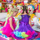 Smiling girl in the limited-edition MADMIA Wonderland Dress featuring pink tulle, colorful frills, and whimsical details.