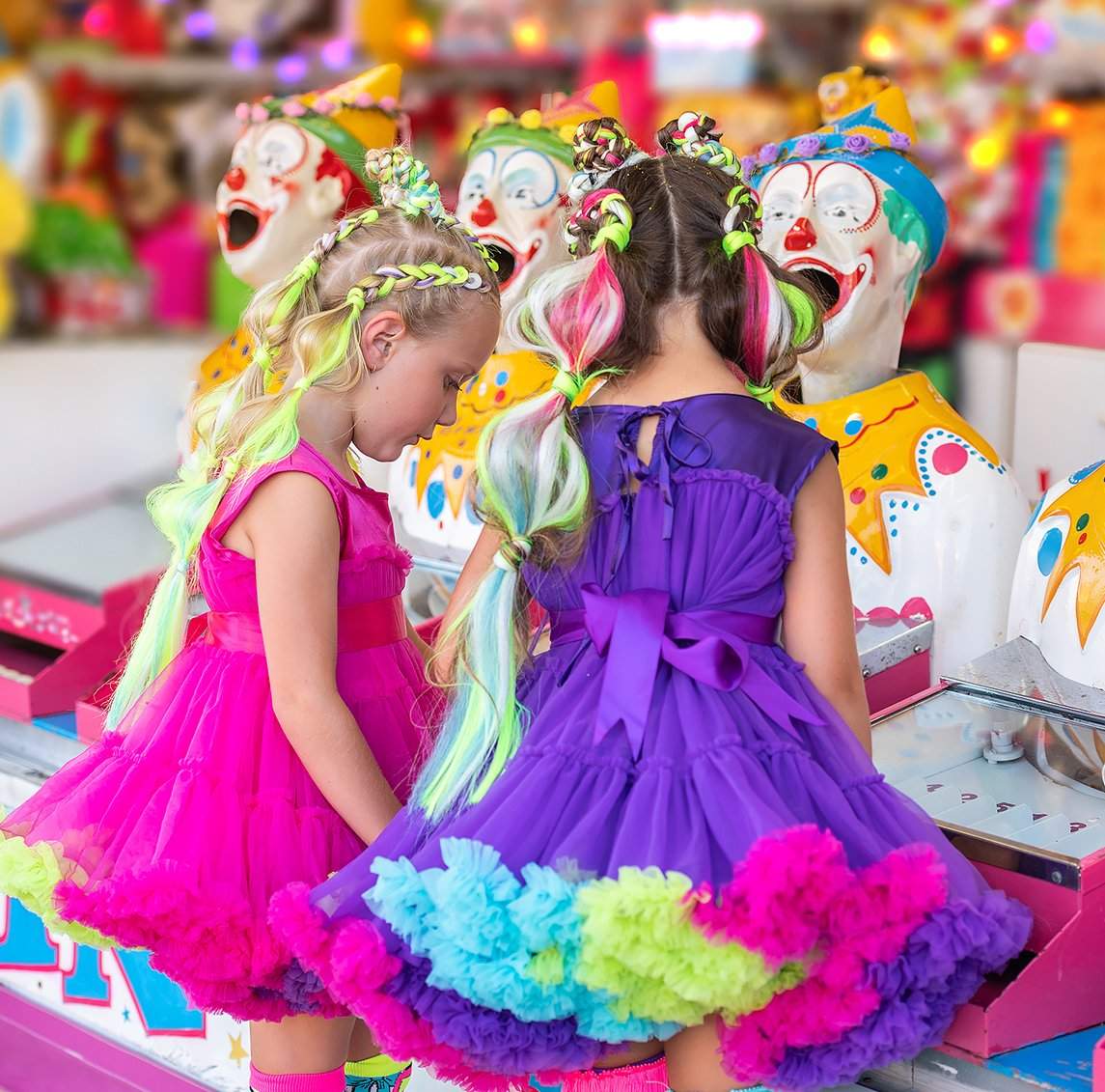Smiling girl in the limited-edition MADMIA Wonderland Dress featuring pink tulle, colorful frills, and whimsical details.