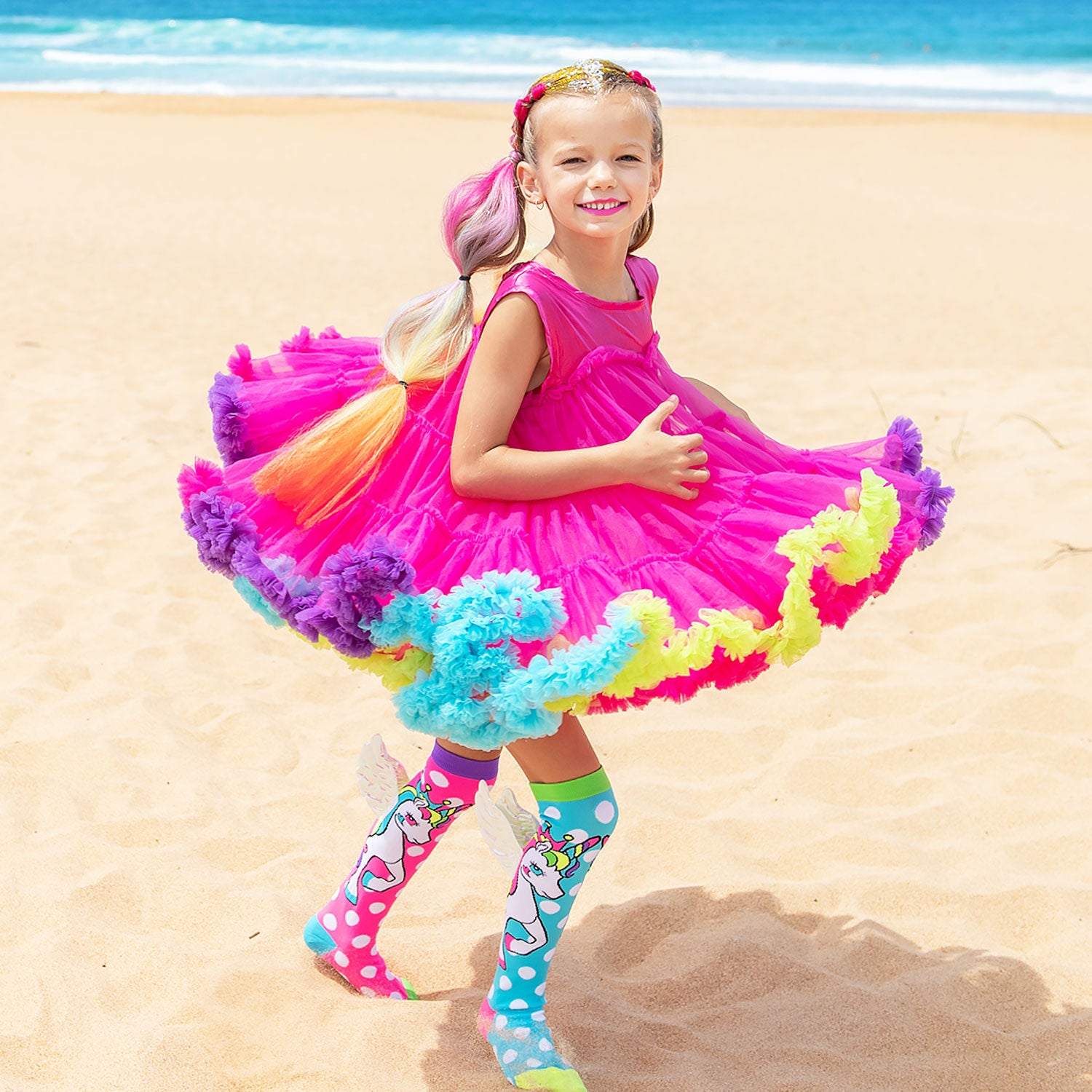 Girl wearing the MADMIA Wonderland Dress with pink rainbow tulle layers and playful frills for parties and birthdays.